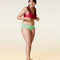 Woman wearing a red sports bra and green underwear on a gradient background
