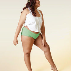 Woman wearing a white top and green underwear on a gradient background