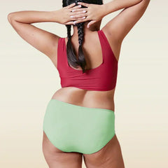 Person wearing a red top and green high-waisted bikini bottom on a beige background