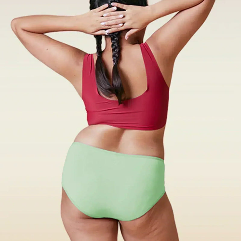 Person wearing a red top and green high-waisted bikini bottom on a beige background