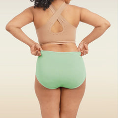 Person wearing a beige sports bra and green high-waisted breifs on a neutral background