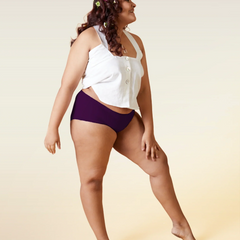 Woman wearing a white top and  violet mid-waist underwear on a beige background