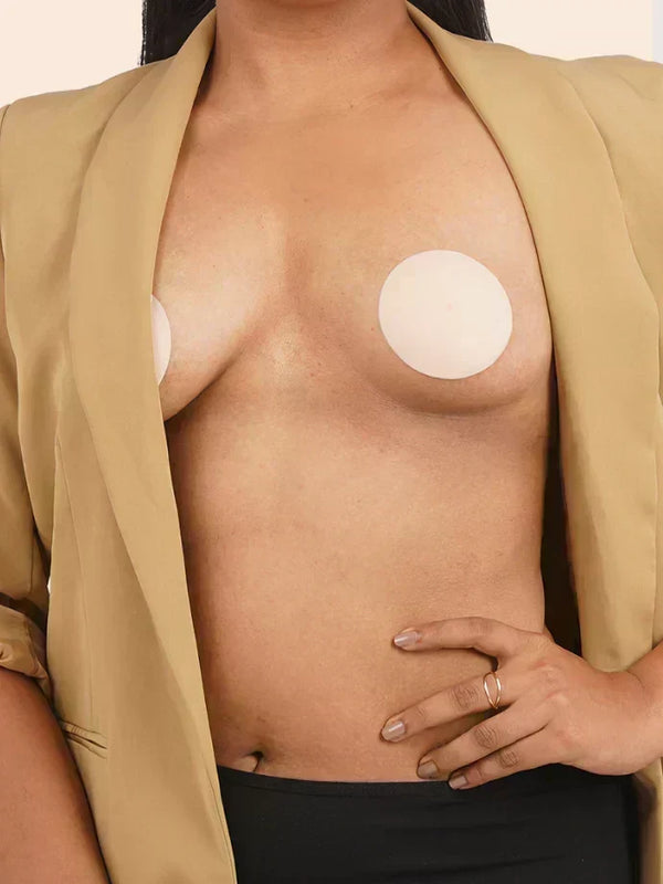 Person wearing a beige blazer with silicone nipple patches on their chest.