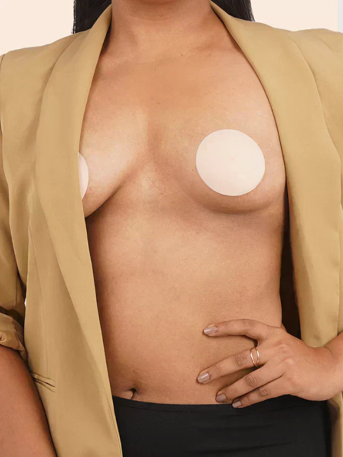 Person wearing a beige blazer with silicone nipple patches on their chest.