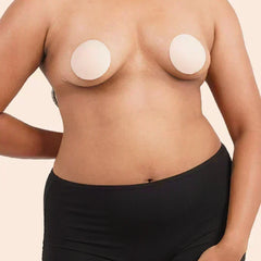 Person wearing a black underwear with silicone nipple patches on a beige background