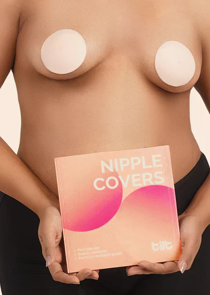 Person holding a box of nipple covers with 'tilt' branding on a neutral background