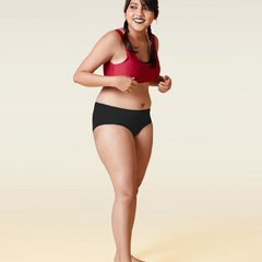 Woman wearing a red sports bra and black underwear on a beige background