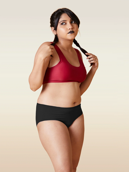 Woman wearing a red sports bra and black underwear on a beige background