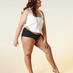 Woman wearing a white top and black underwear on a beige background
