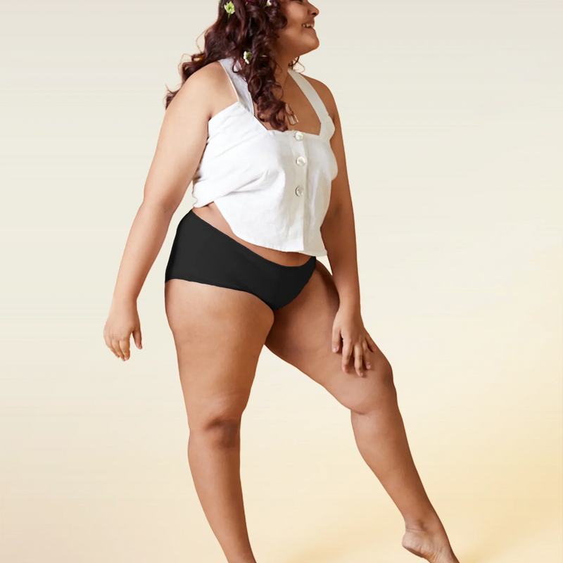 Woman wearing a white top and black underwear on a beige background