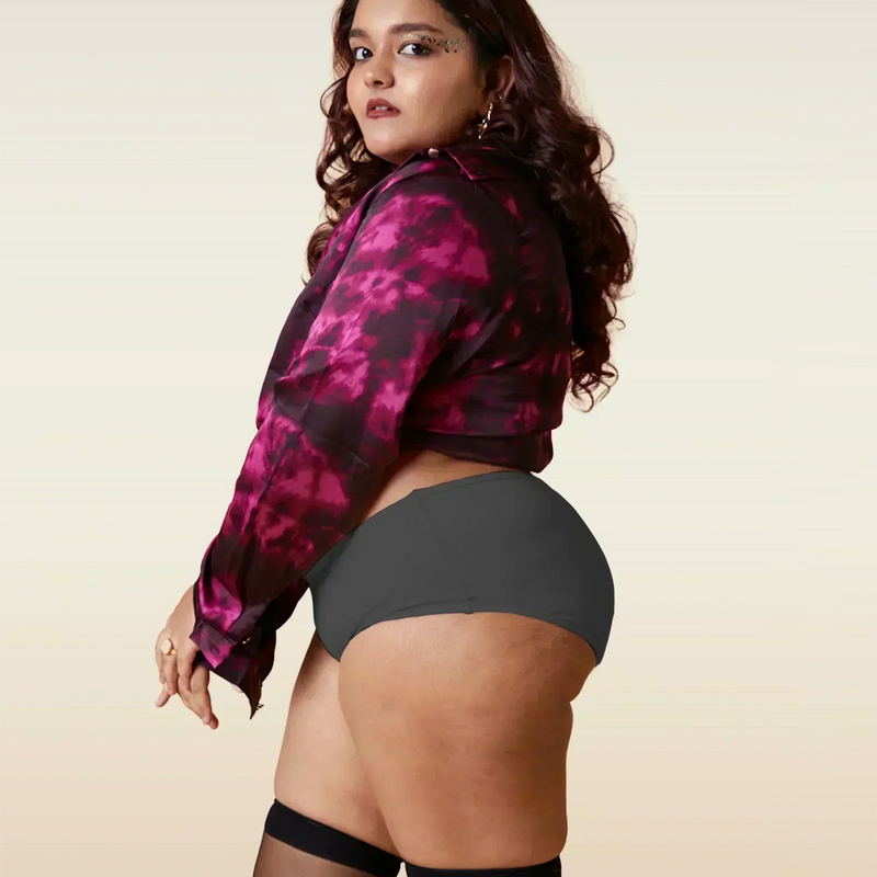 Woman wearing a pink and black patterned jacket with gray underwear and black stockings on a beige background