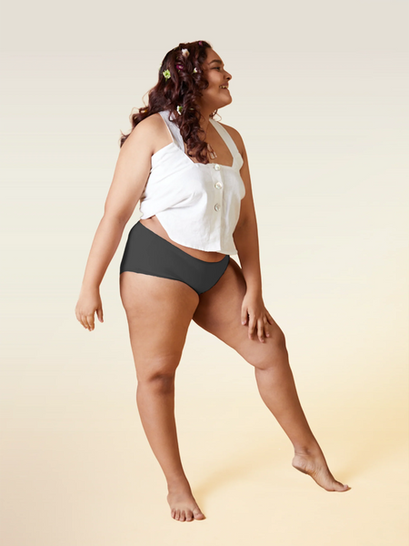 Woman wearing a white top and gray underwear on a beige background