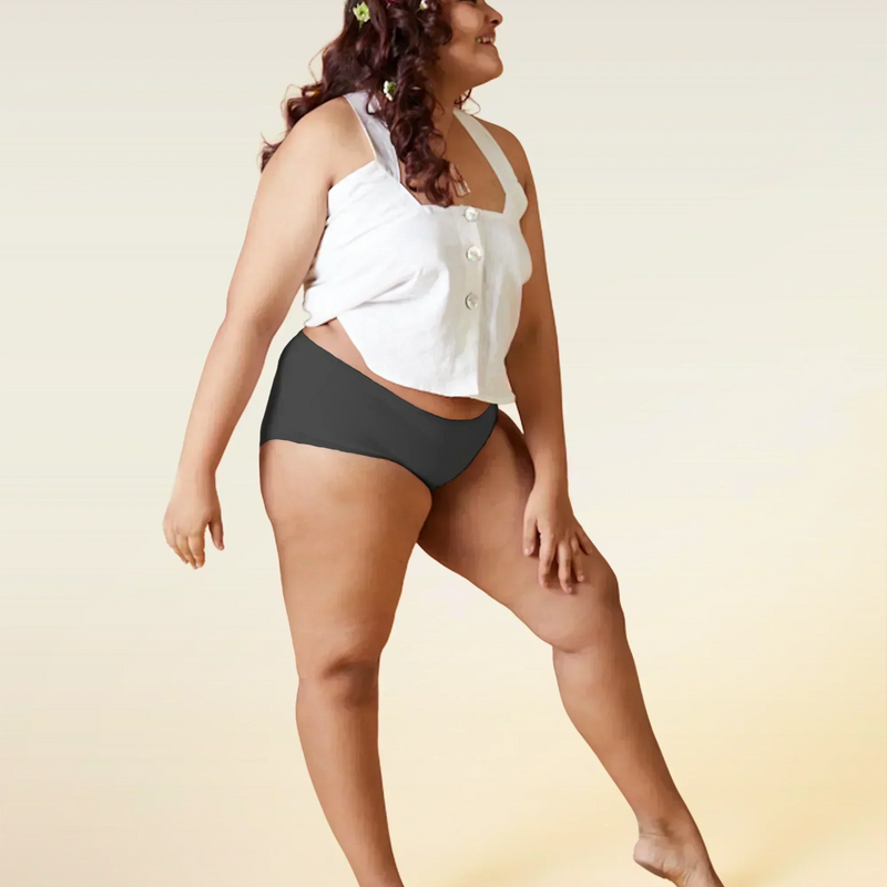 Woman wearing a white top and gray underwear on a beige background