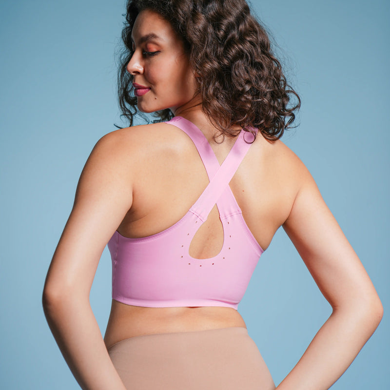 Woman wearing a pink sports bra and beige underwear against a blue background