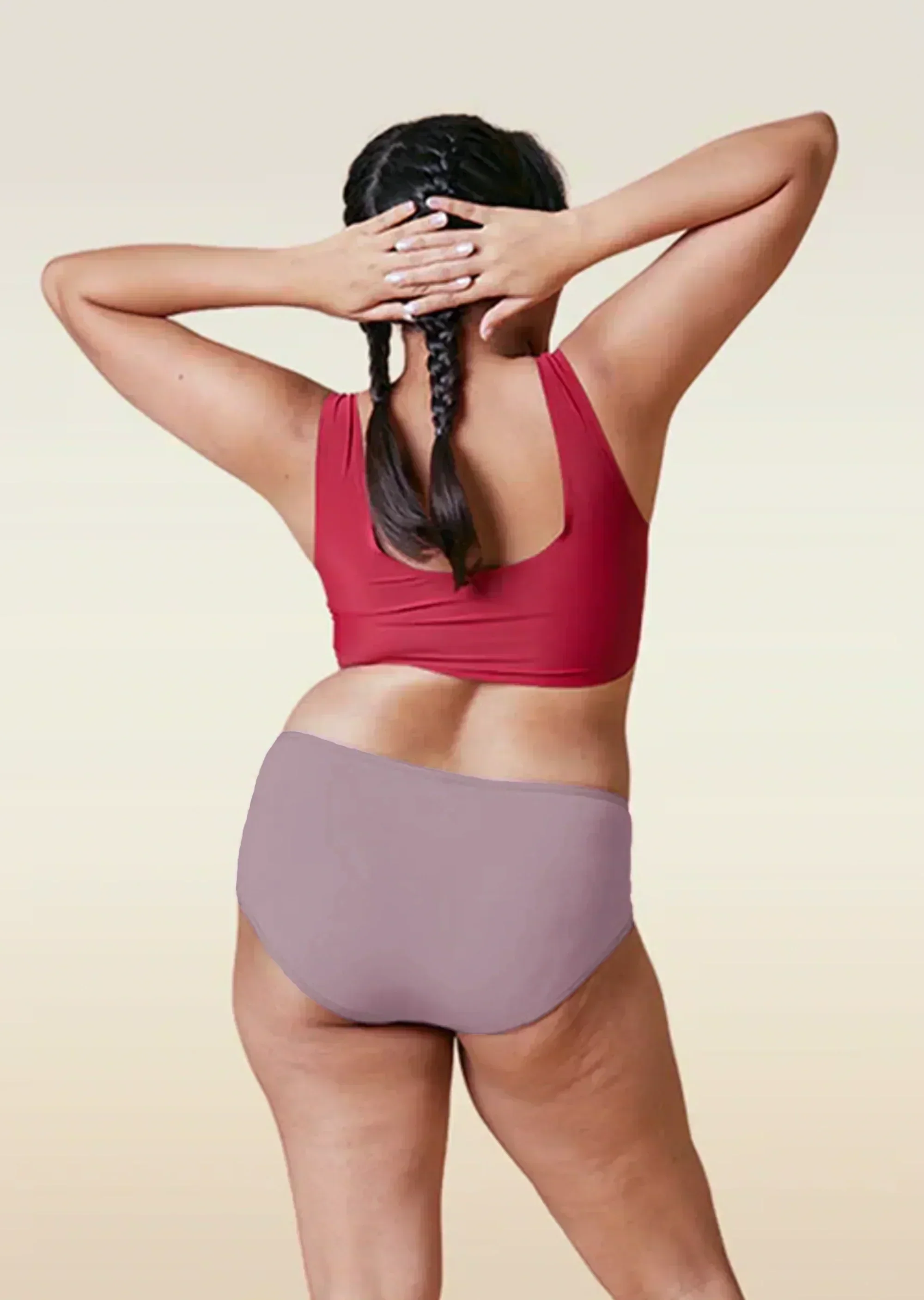 Person wearing a red sports bra and brown high-waisted underwear on a beige background