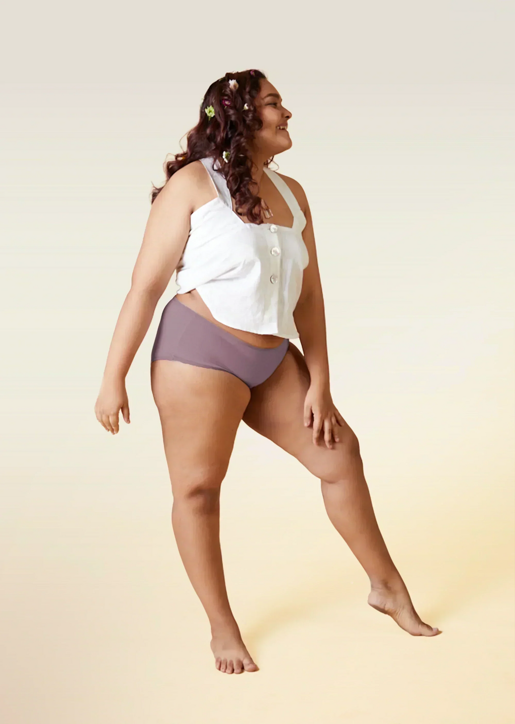 Woman wearing a white top and brown underwear on a beige background