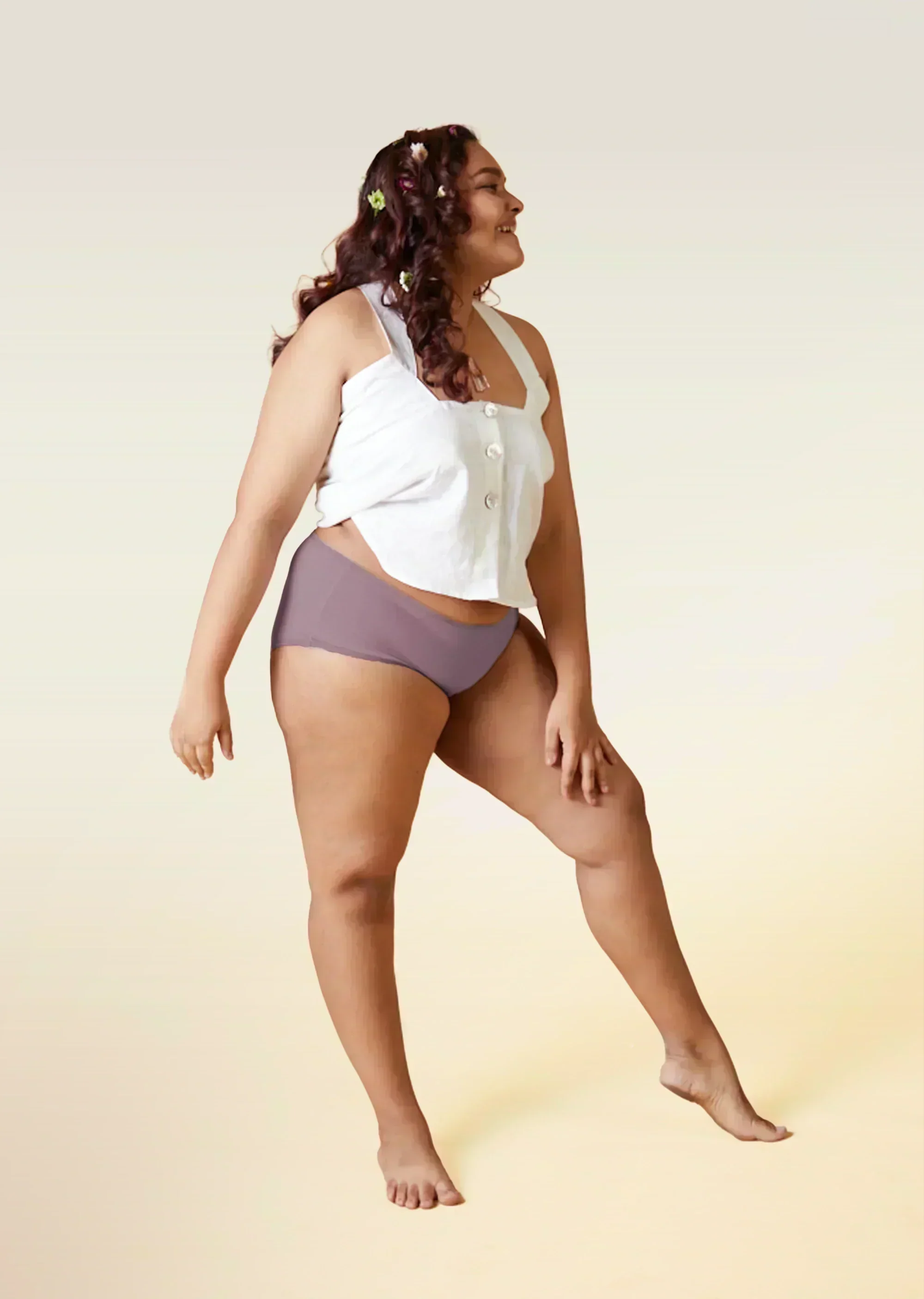 Woman wearing a white top and brown underwear on a beige background