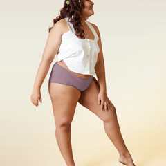 Woman wearing a white top and brown underwear on a beige background