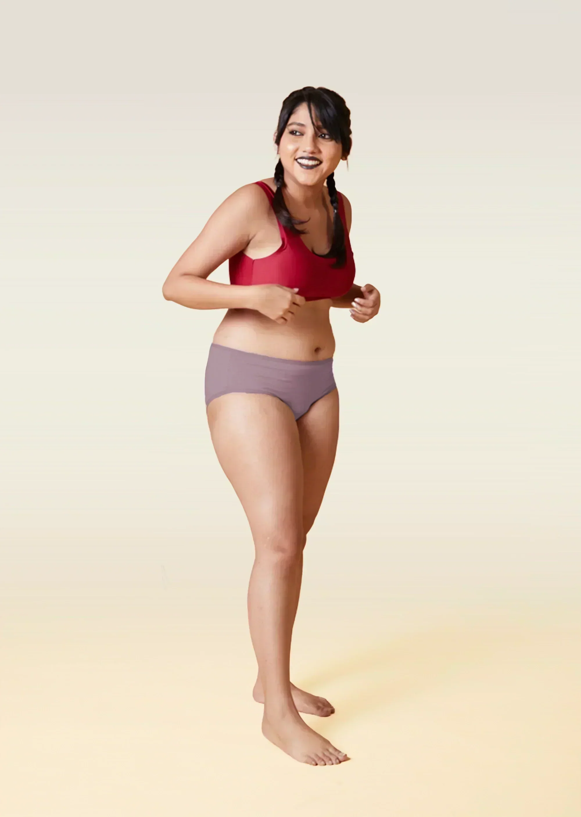 Woman wearing a red sports bra and brown underwear on a gradient background