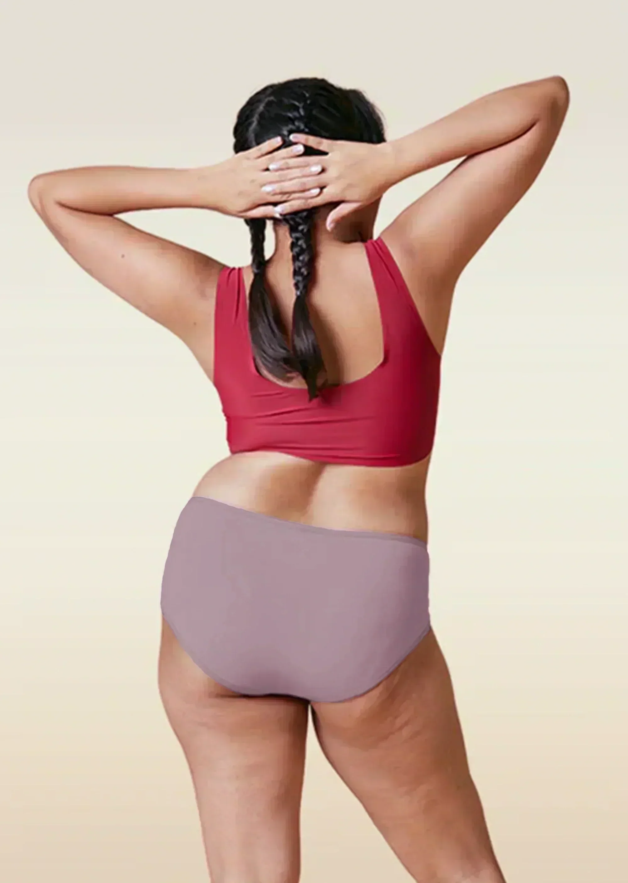 Person wearing a red sports bra and brown high-waisted underwear on a beige background