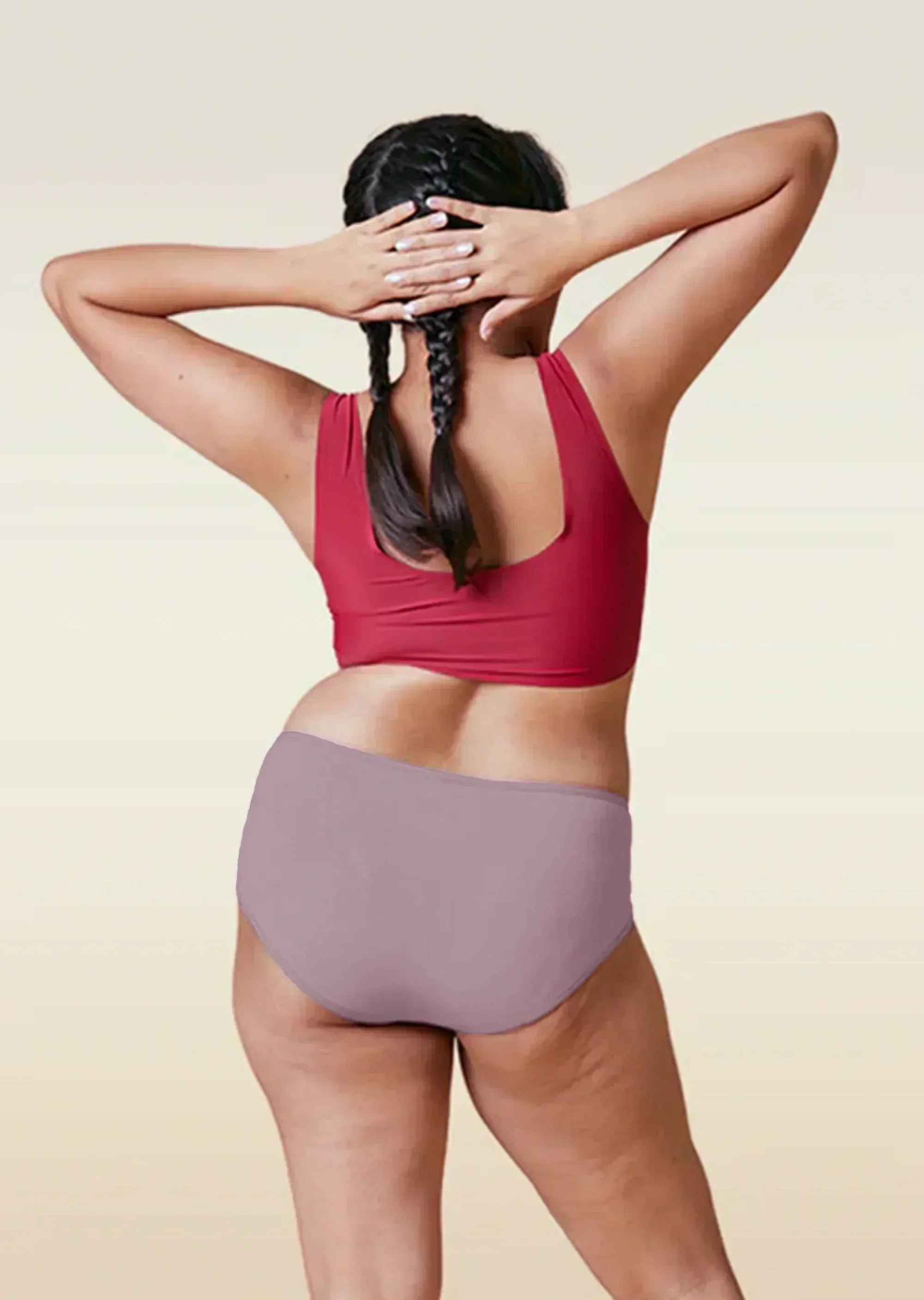 Person wearing a red sports bra and brown high-waisted underwear on a beige background