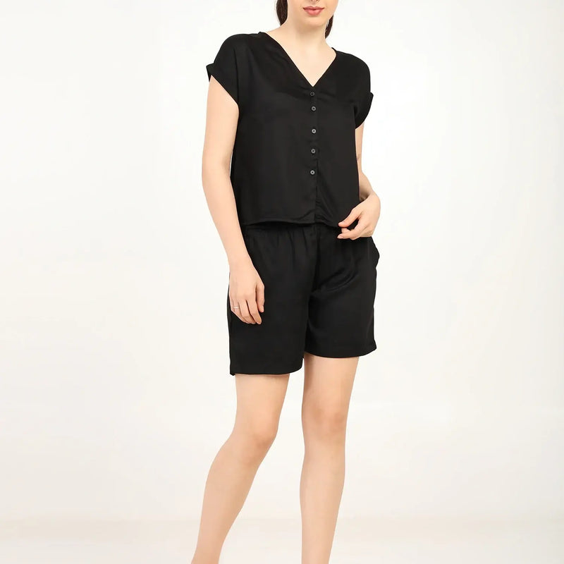 Model wearing Women's Modal Satin Night Suit in black, featuring a soft button-up shirt and shorts, perfect for sleepwear.