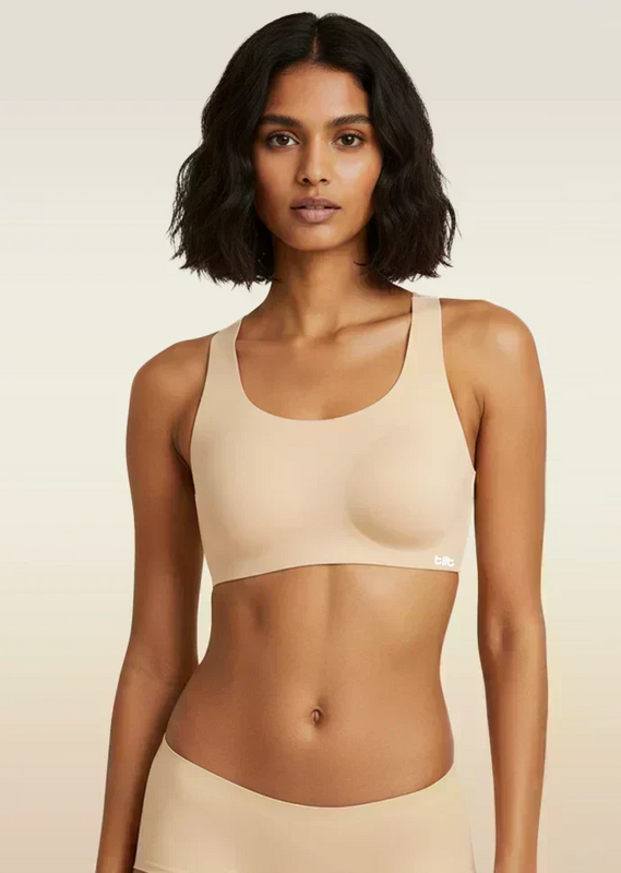 Woman wearing a beige sports bra and panties on a plain background