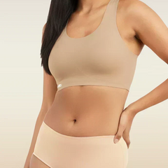 Woman wearing a beige sports bra and mid-waist underwear set on a neutral background