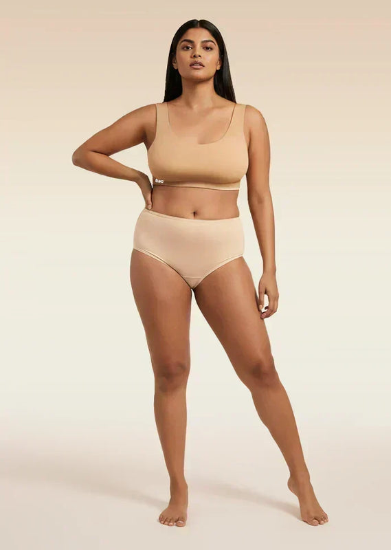 Woman wearing a beige bra and underwear set on a beige background