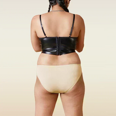 Person wearing a black leather corset and beige underwear on a beige background