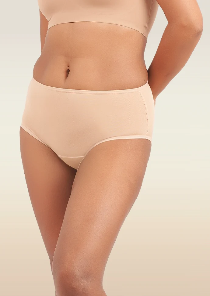 Person wearing beige mid-waist underwear on a plain background