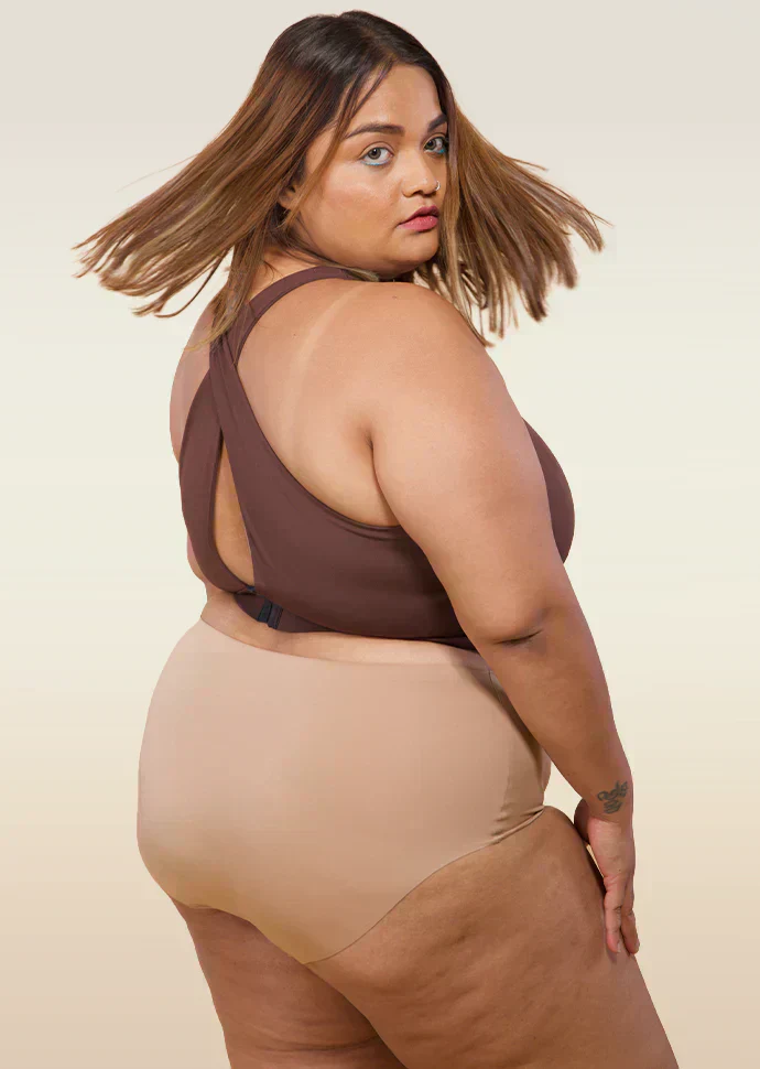 Woman wearing a brown sports bra and beige underwear on a beige background