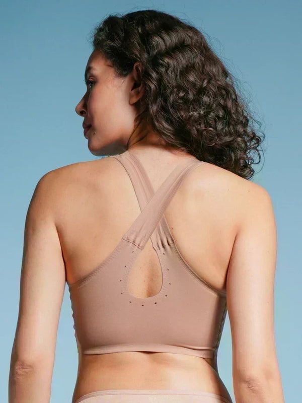 Woman wearing a beige sports bra against a blue background