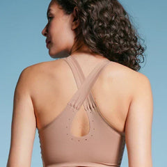 Woman wearing a beige sports bra against a blue background
