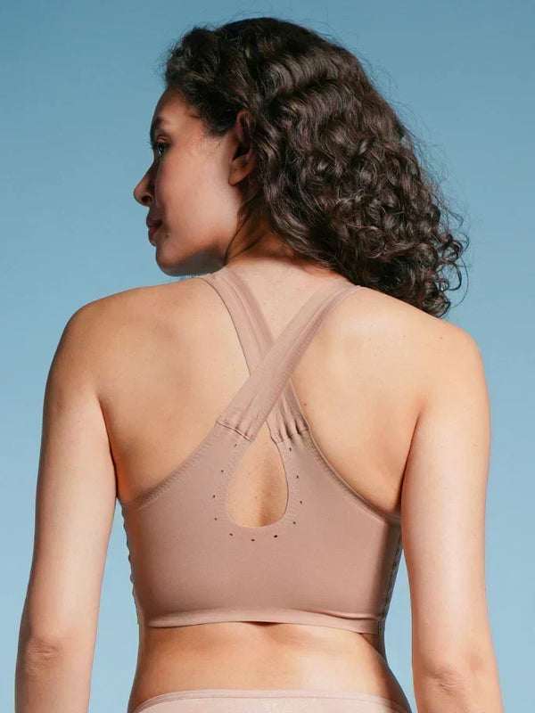 Woman wearing a beige sports bra against a blue background