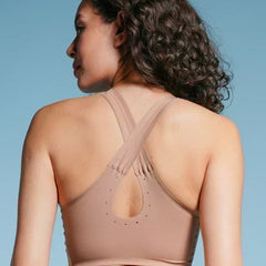 Woman wearing a beige sports bra against a blue background