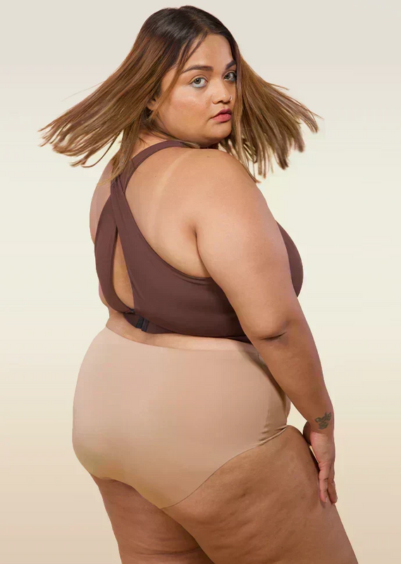 Woman wearing a brown sports bra and beige underwear on a beige background