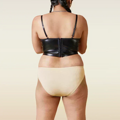 Person wearing a black leather corset and beige underwear on a beige background