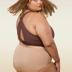 Woman wearing a brown sports bra and beige underwear on a beige background