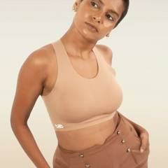 Woman wearing a beige bra and brown pants against a plain background