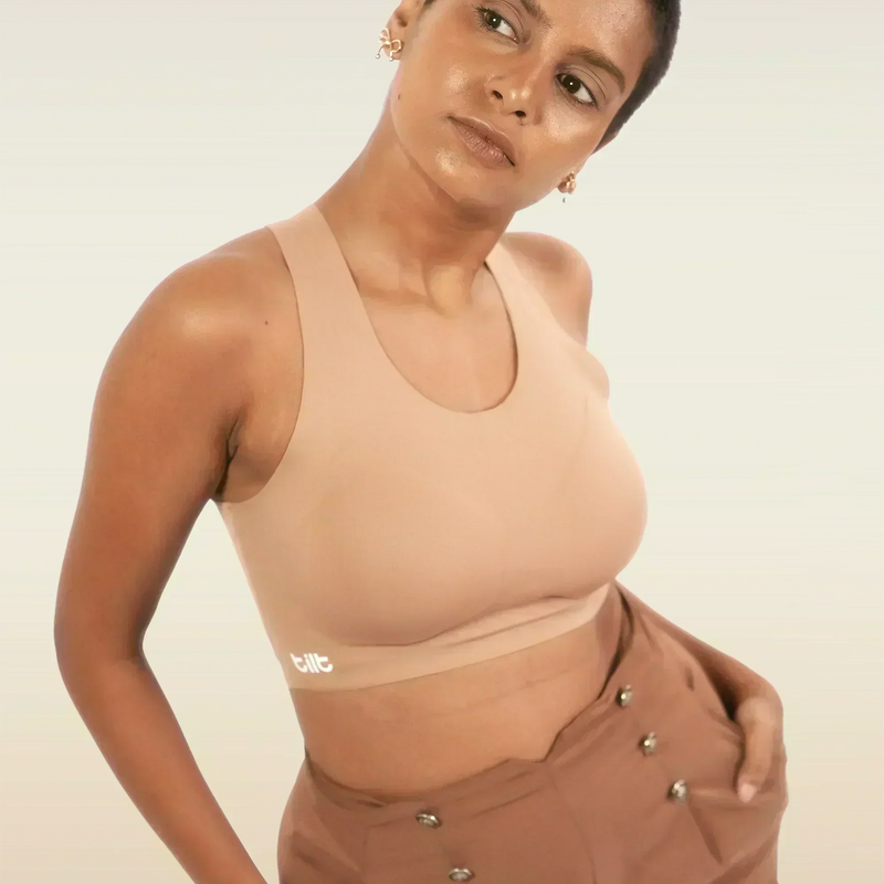 Woman wearing a beige bra and brown pants against a plain background