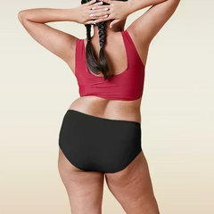 Person wearing a red sports bra and black underwear on a beige background
