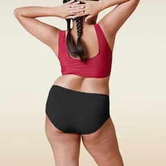 Person wearing a red sports bra and black underwear on a beige background
