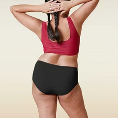 Person wearing a red sports bra and black underwear on a beige background