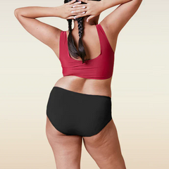 Person wearing a red sports bra and black underwear on a beige background