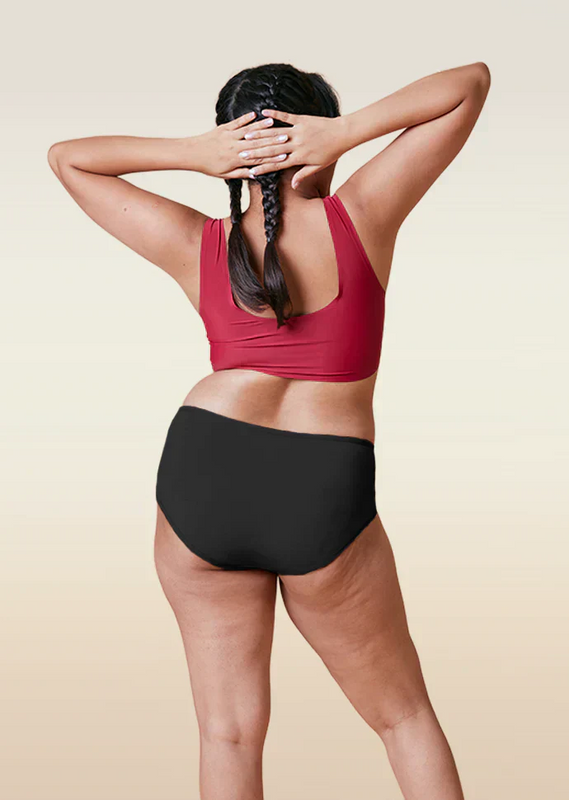 Person wearing a red sports bra and black underwear on a beige background