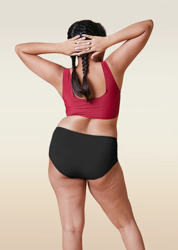 Person wearing a red sports bra and black underwear on a beige background