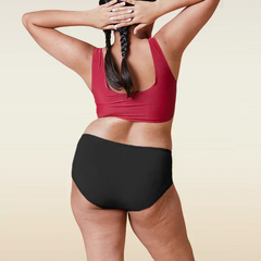 Person wearing a red sports bra and black underwear on a beige background