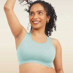 Woman wearing a blue sports bra and pink underwear on a beige background
