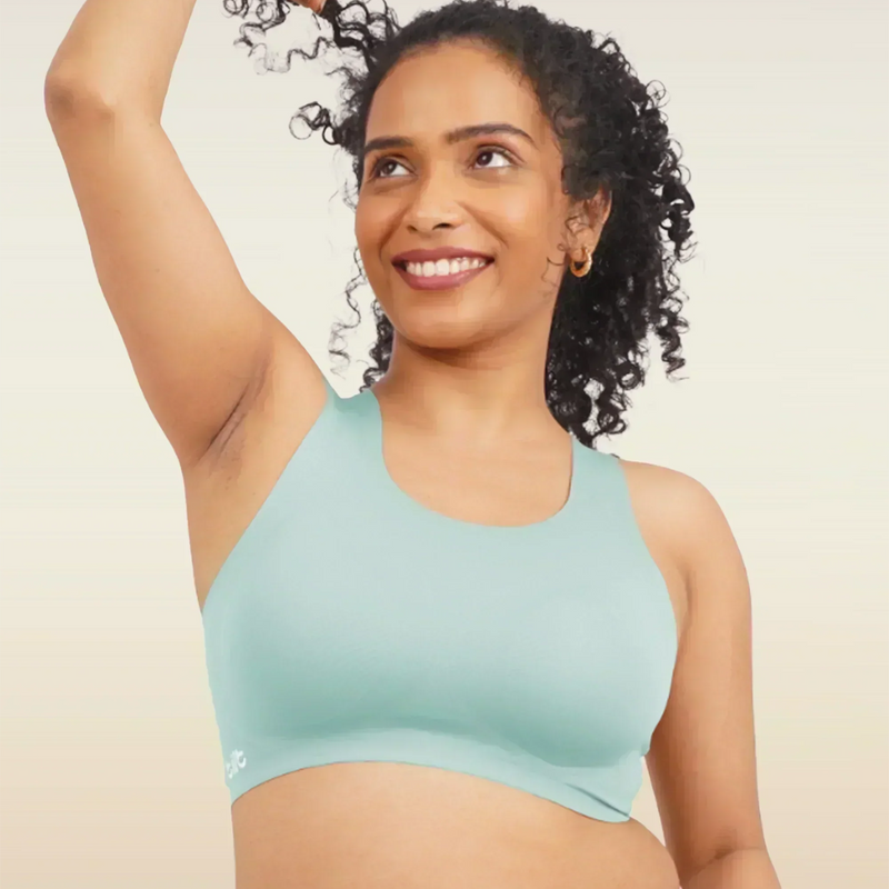 Woman wearing a blue sports bra and pink underwear on a beige background